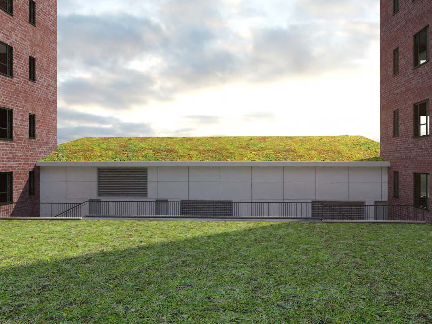 Campus-side view of the StuyTown energy building, a low white volume with louvered openings and a sloped vegetated roof, sitting behind a simple metal railing and lawn.