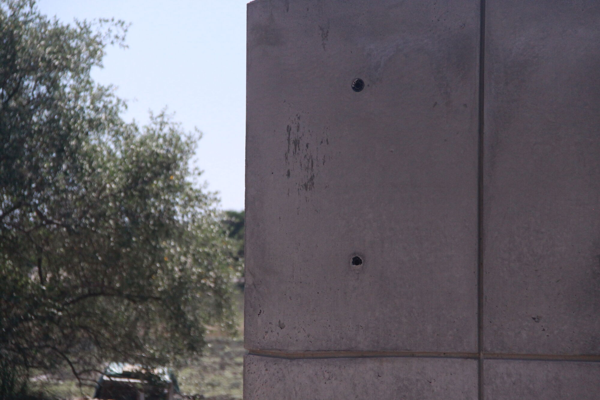 Concrete wall panel with evenly spaced open tie holes and a vertical reveal.