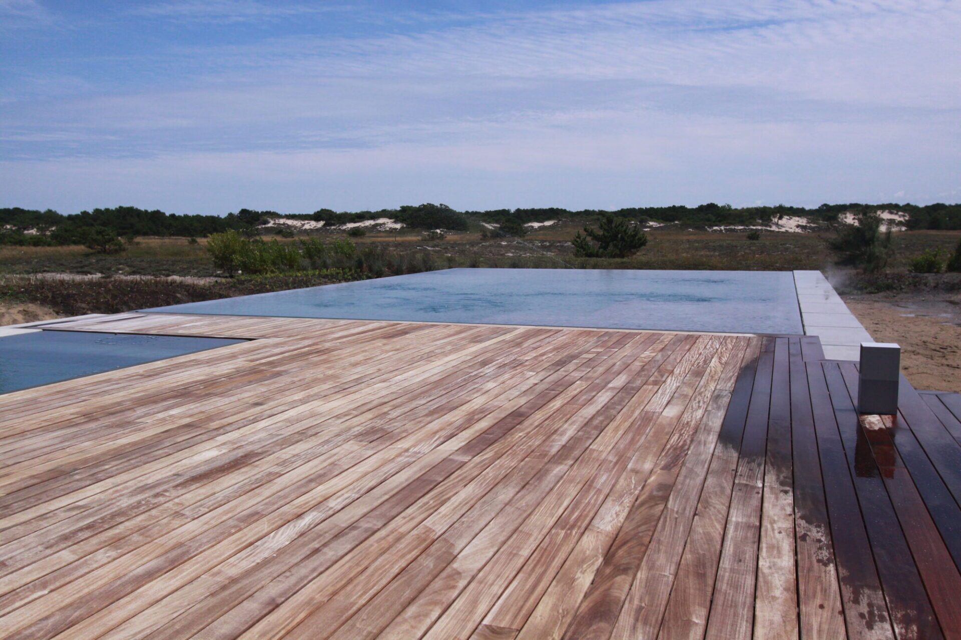 Close view along an ipe deck to the edge of a pool whose water sits flush with the deck surface.