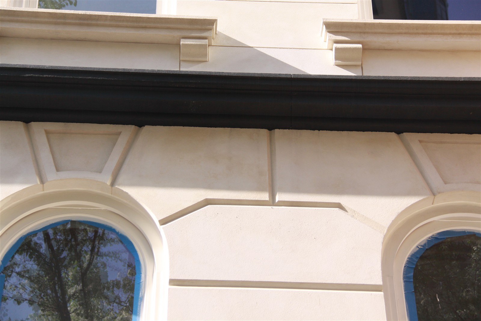 Finished stucco facade with control joints tracing the brownstone pattern around arched windows