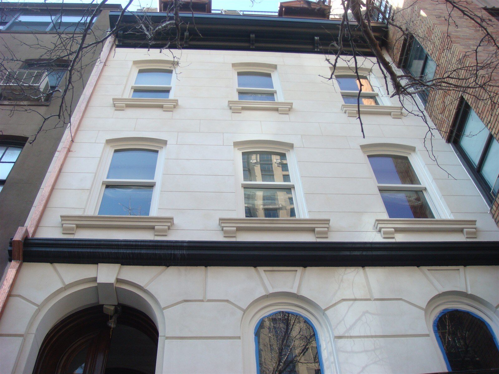 Finished front facade of the Kim Eng Townhouse in Midtown East, Manhattan, with light stucco, window sills and control joints tracing the brownstone pattern