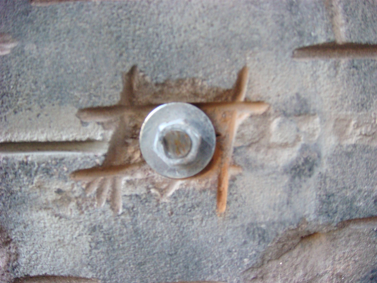 Stainless steel anchor with washer set into scored brownstone to pin the slab back to the brick wall